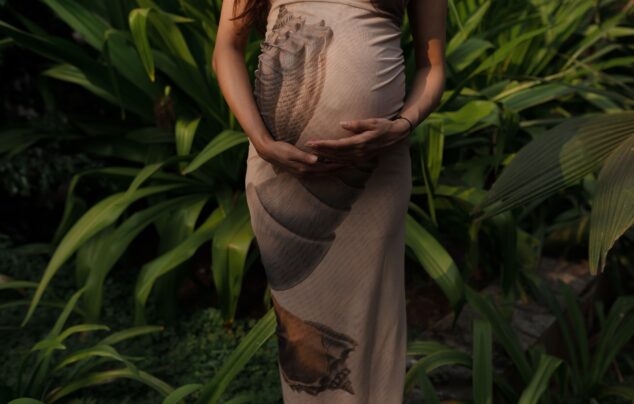 Expectant mother embracing nature in a lush green garden.