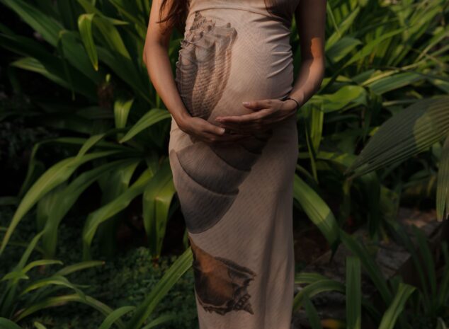 Expectant mother embracing nature in a lush green garden.