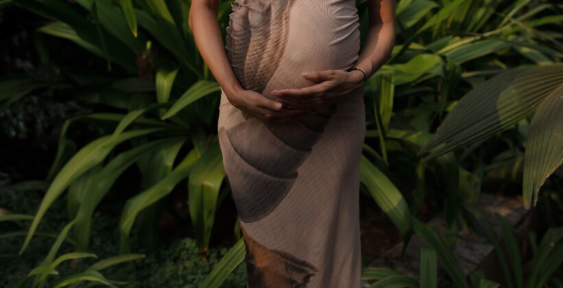 Expectant mother embracing nature in a lush green garden.