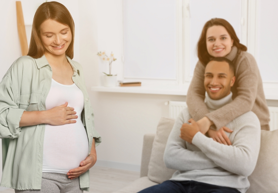 A surrogate is standing up, and a couple is behind embracing each other.