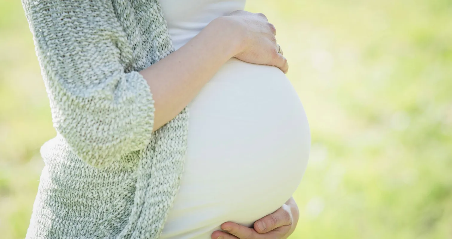 Pregnant woman holding her belly in soft light