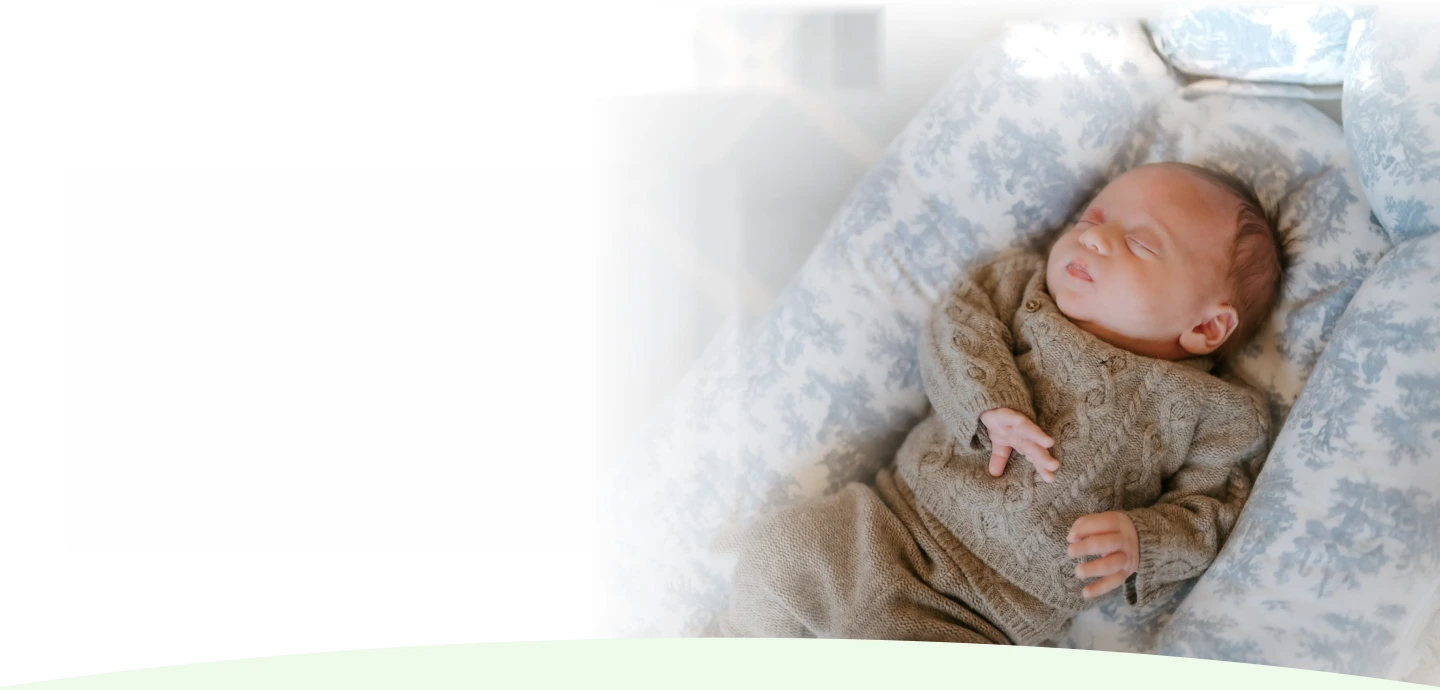 Sleeping newborn baby swaddled in a knit onesie