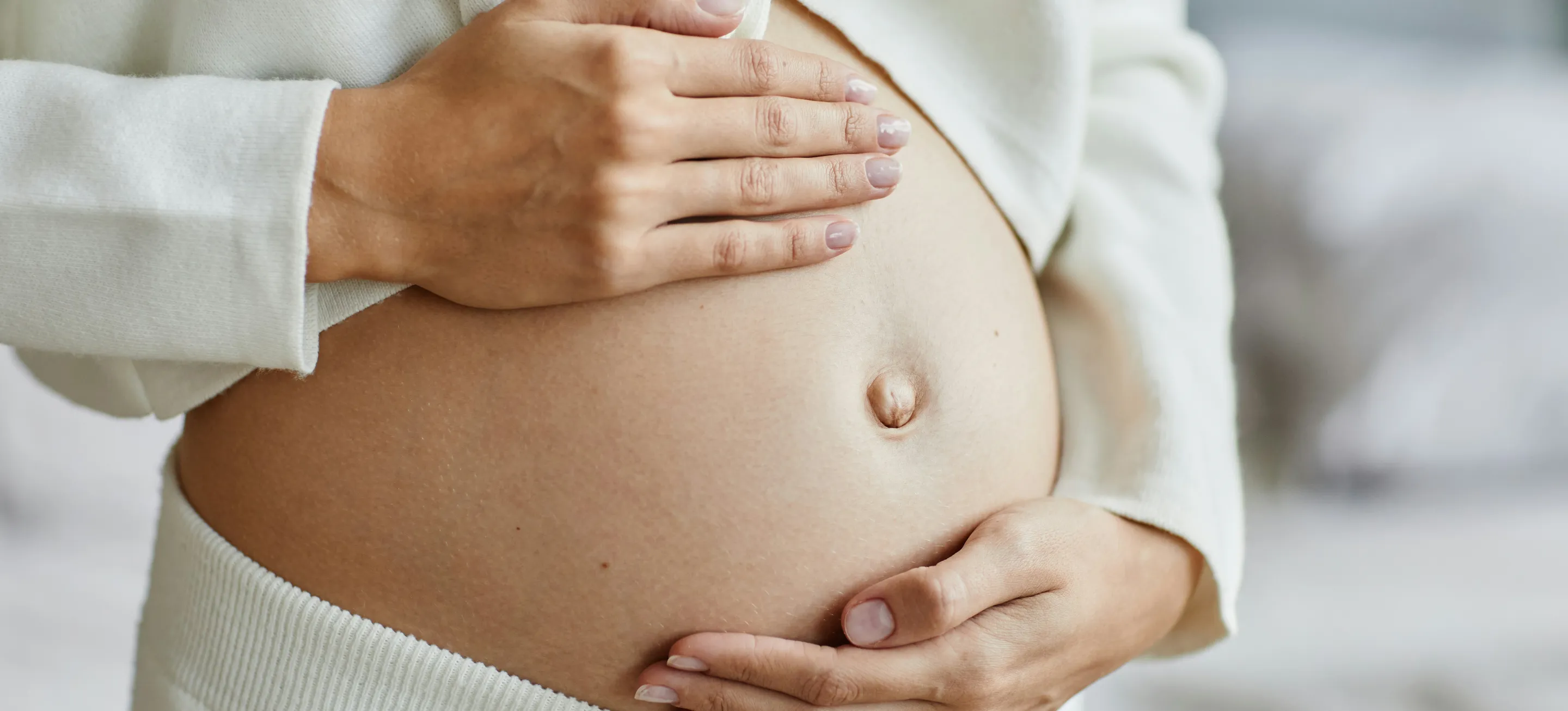 Pregnant woman cradling her belly with both hands