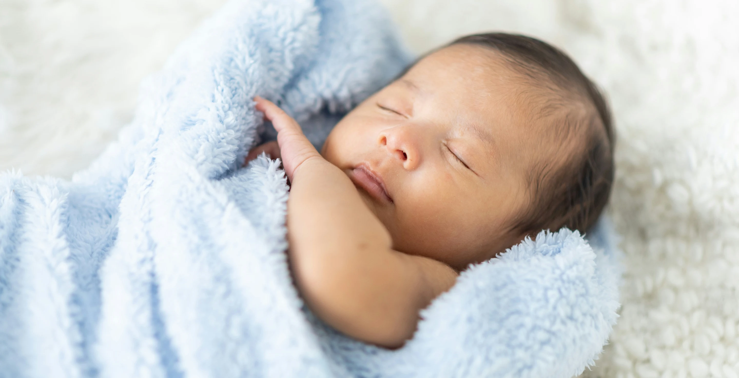 Sleeping newborn baby wrapped in a blue floral blanket