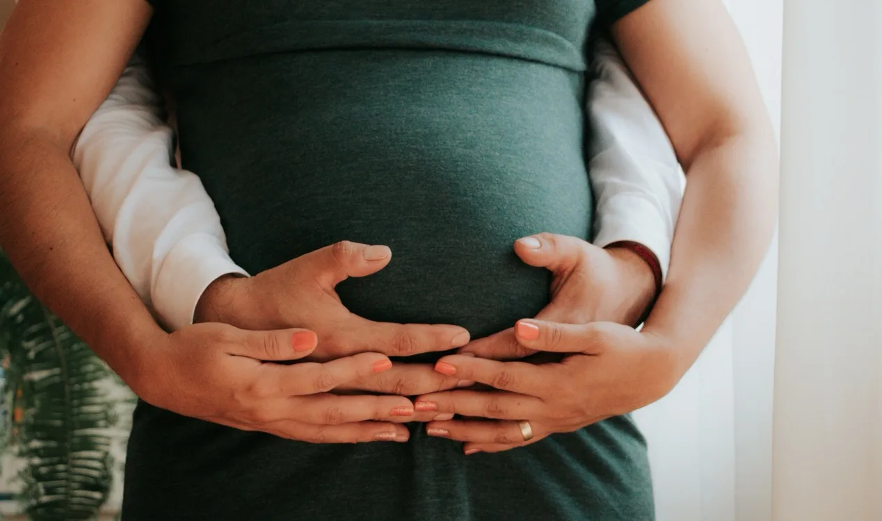 Couple embracing, hands resting together on a pregnant belly