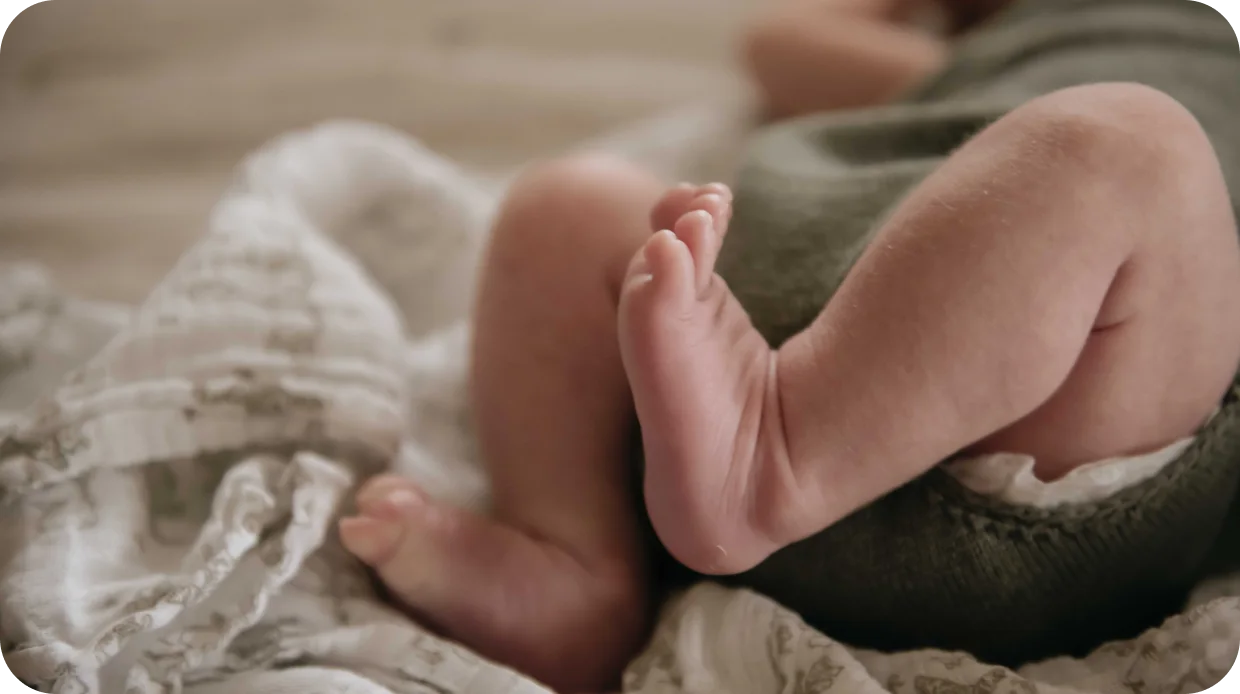 A newborn's feet curled up in a soft knitted blanket