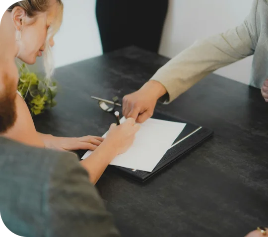 A couple signing paperwork with an attorney at a table