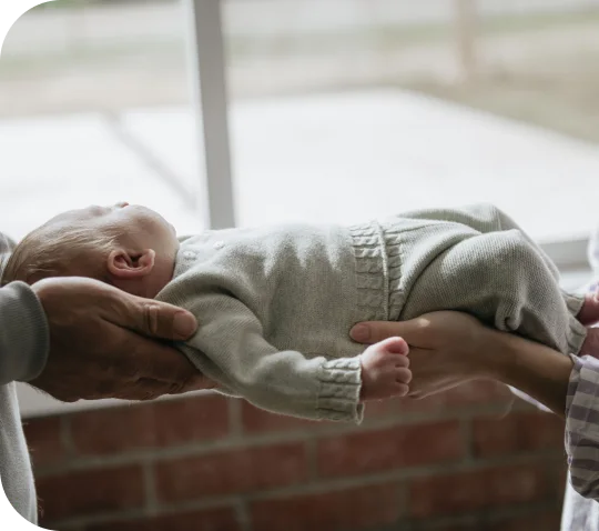 A newborn asleep in an adult's arms