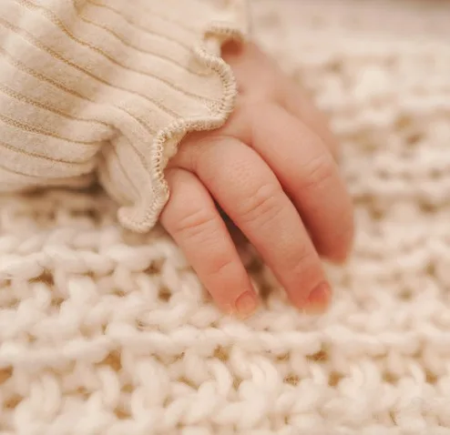 Newborn's hand held by a parent