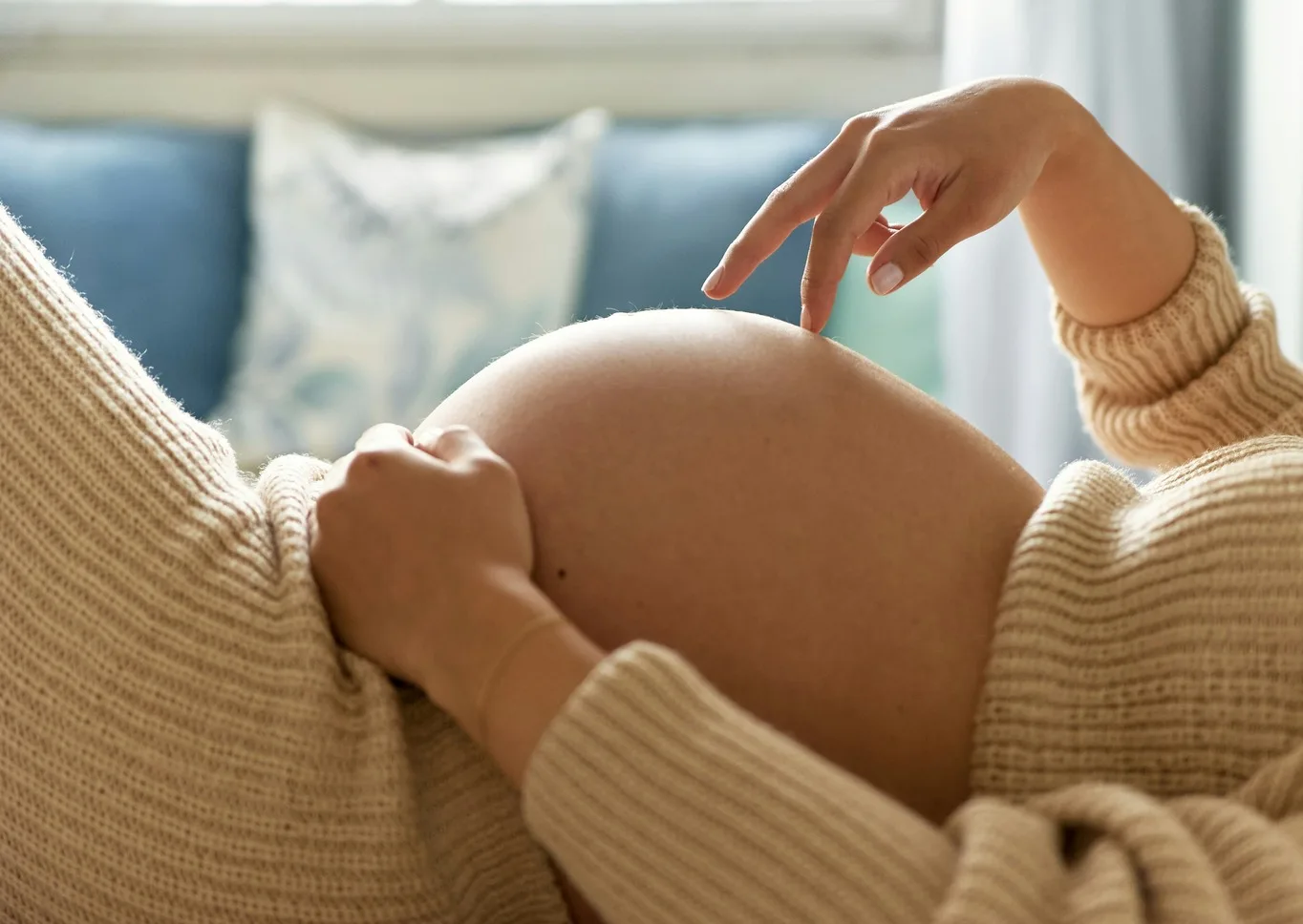 Pregnant woman relaxing on a sofa with a hand on her belly