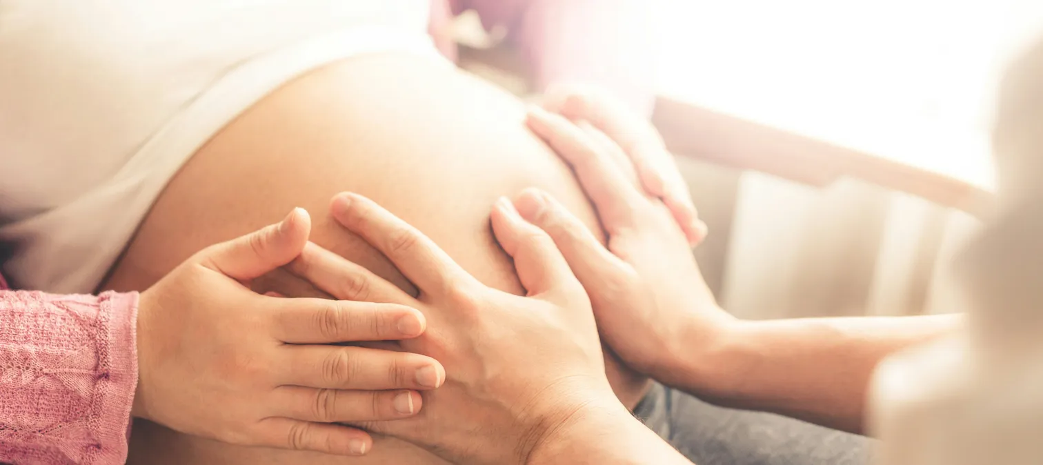 Hands gently cradling a pregnant belly