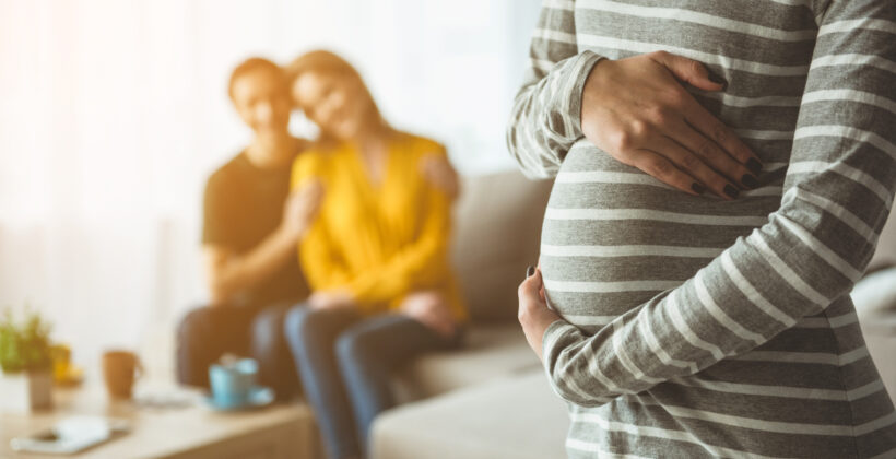 Future parents looking at surrogate expectant mother
