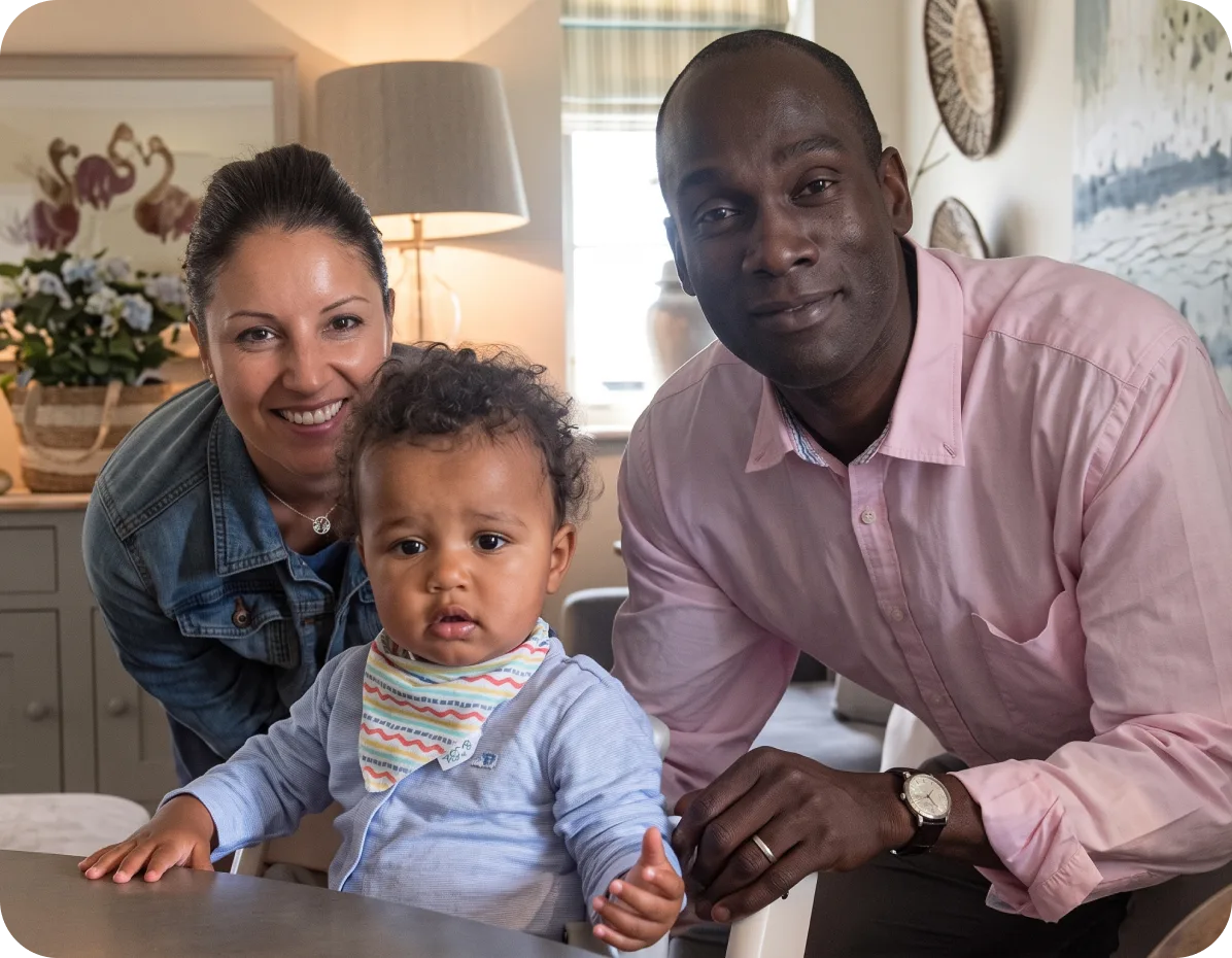 Two parents smiling with their baby son at the kitchen table