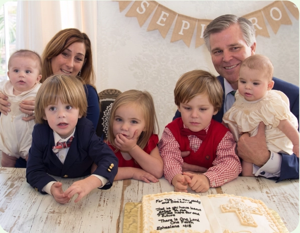 Parents with their five children gathered around a celebration cake
