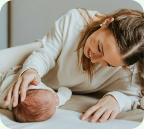 Mother smiling over her newborn on a bed