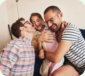 Two fathers laughing with their daughter