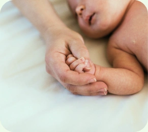 Adult hand holding a newborn's hand